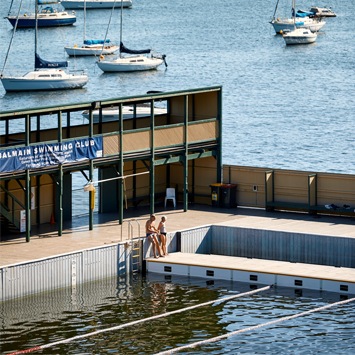  Image from above of DFB with two people standing on the pontoon and boats visibile in the harbour